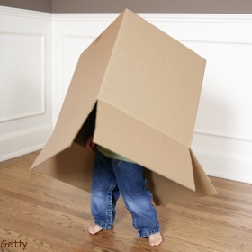 little boy playing with carboard box