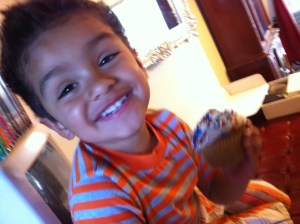 little boy smiling with cupcake on hand